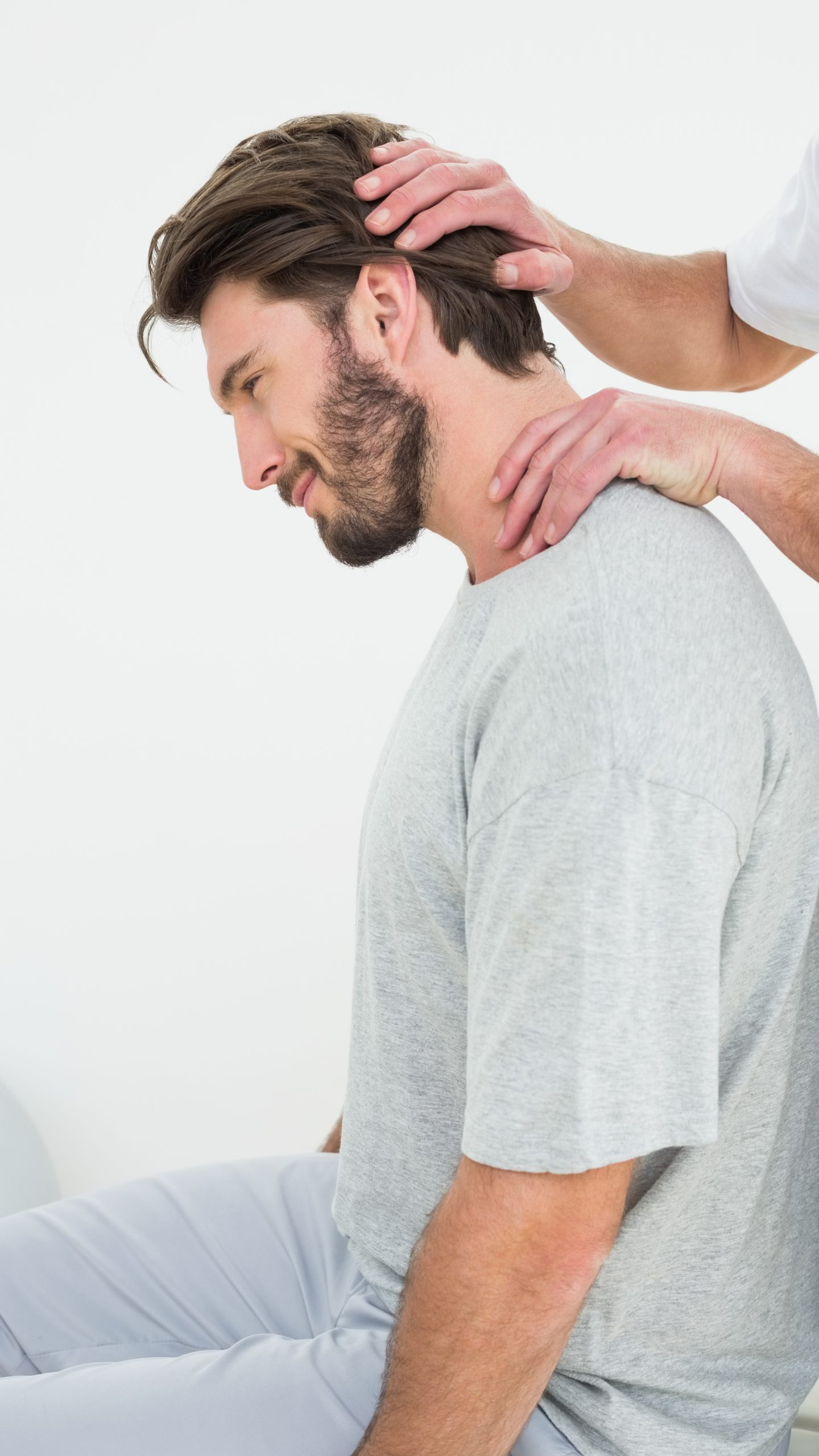 Side view of a young man getting the neck adjustment done in the medical office